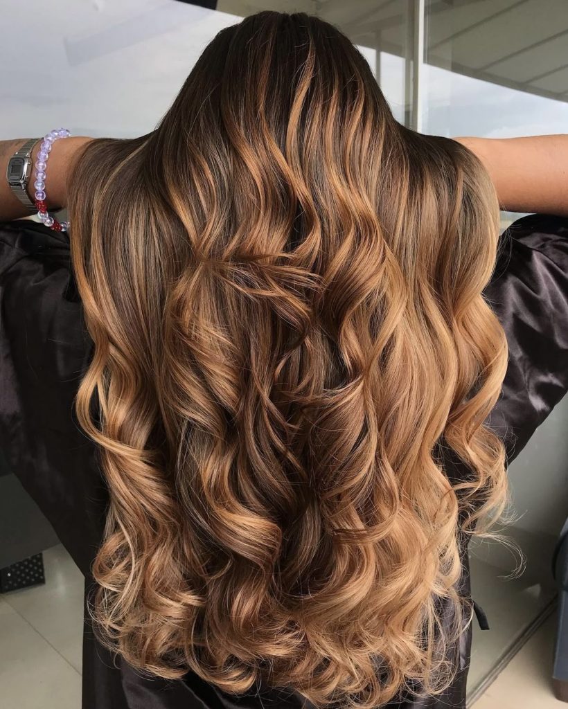  Model with shiny sandy brown hair styled in loose waves under sunlight

