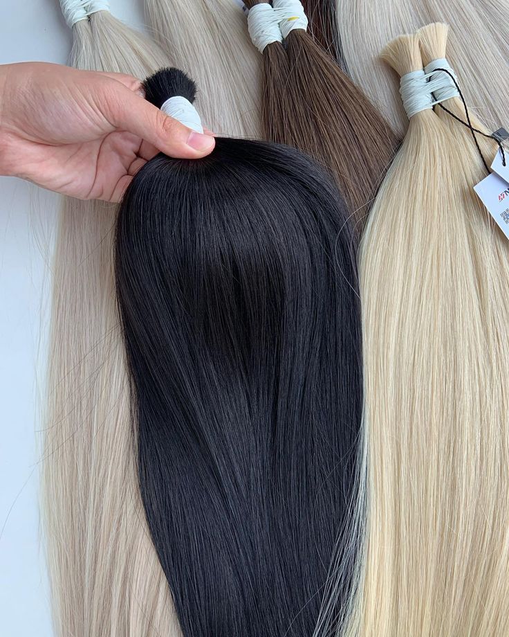 Different types of raw, virgin, remy, and single donor hair bundles displayed on a table